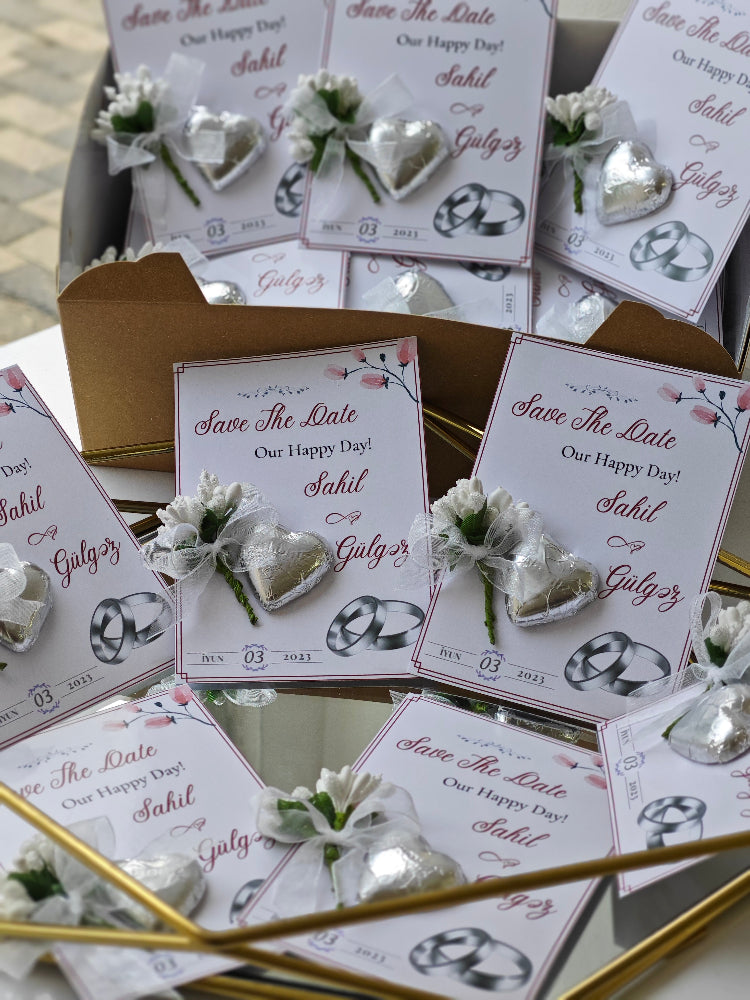 Wedding invitation cards with heart designs and 'Save The Date' text on a reflective surface.