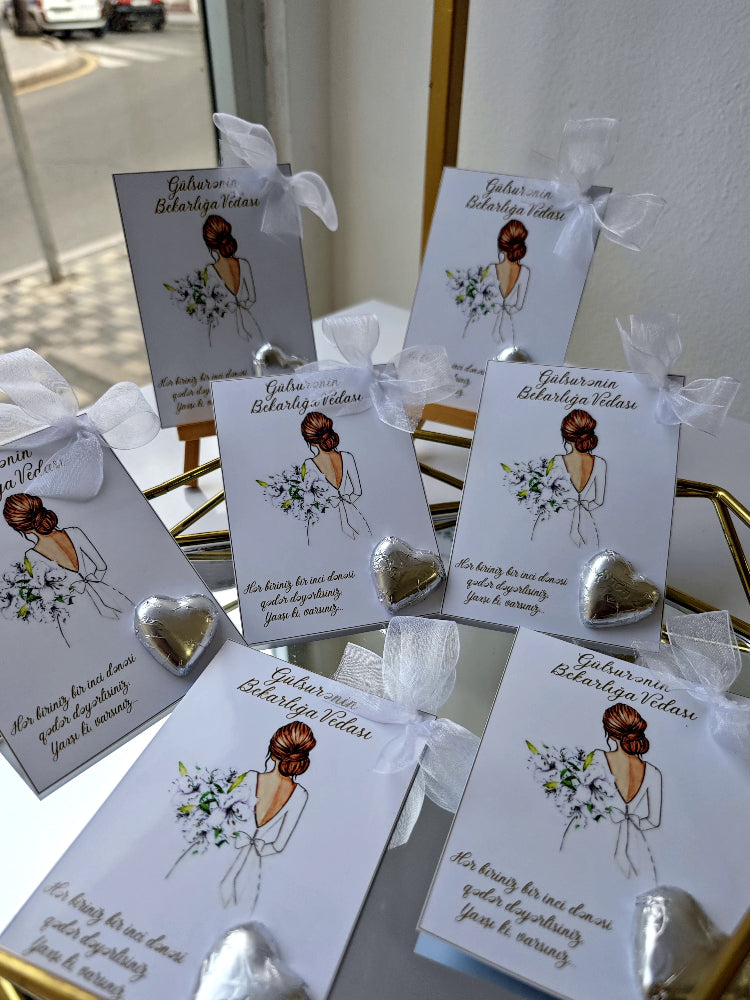 Silver heart-shaped earrings on cards with illustrations and text, displayed on a reflective surface.