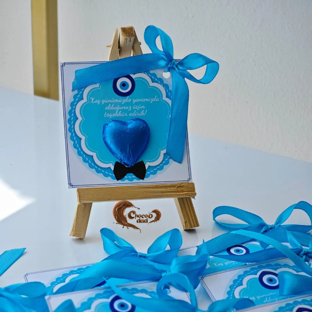 Blue heart-shaped gift with ribbon on a small easel against a white background