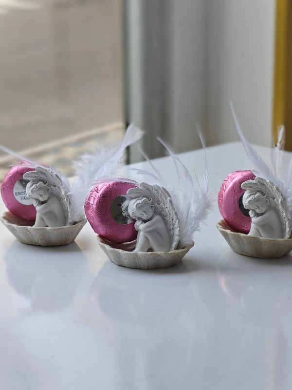 Decorative items with angel figures and pink elements on a white surface