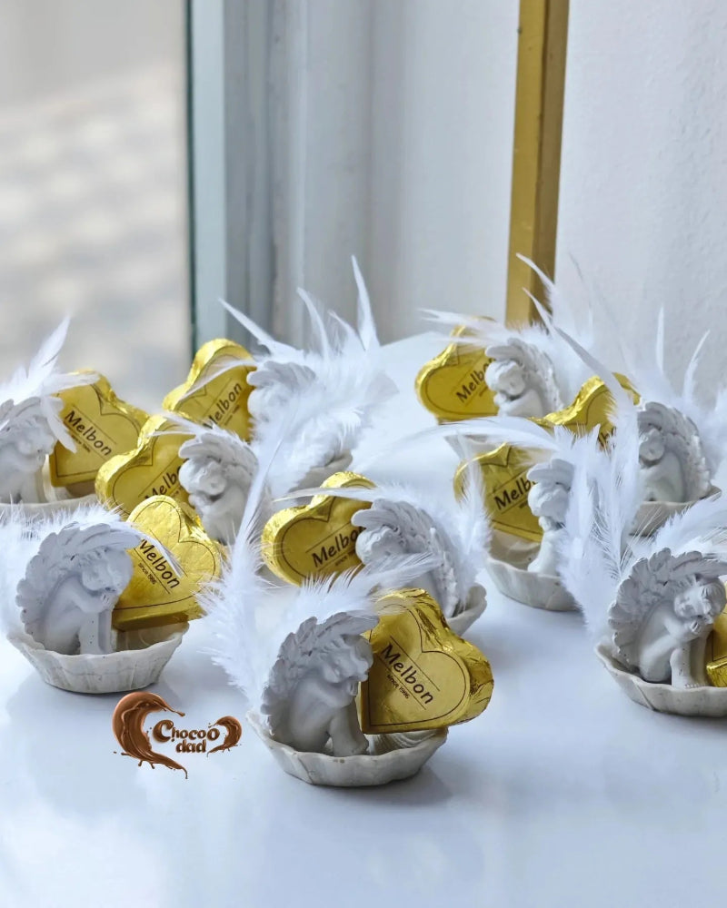 White angel figurines with gold hearts and 'Melbon' branding on a white surface.