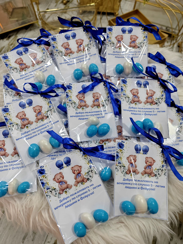 Packaged items with teddy bears and blue ribbons on a textured surface
