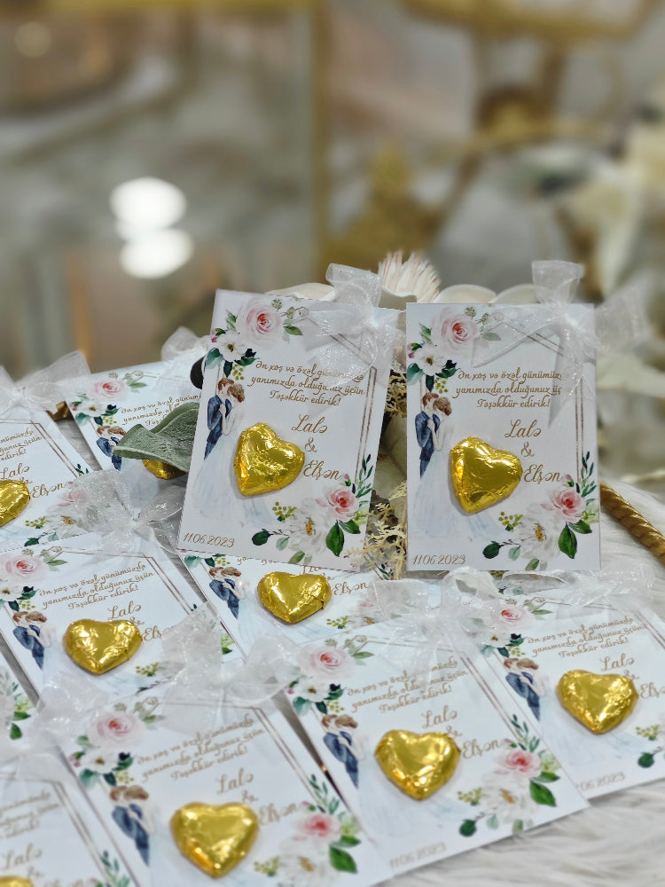 Gold heart-shaped chocolate candies on floral cards with text, placed on a table.