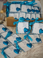 Gift boxes with blue hearts and personalized cards on a textured surface