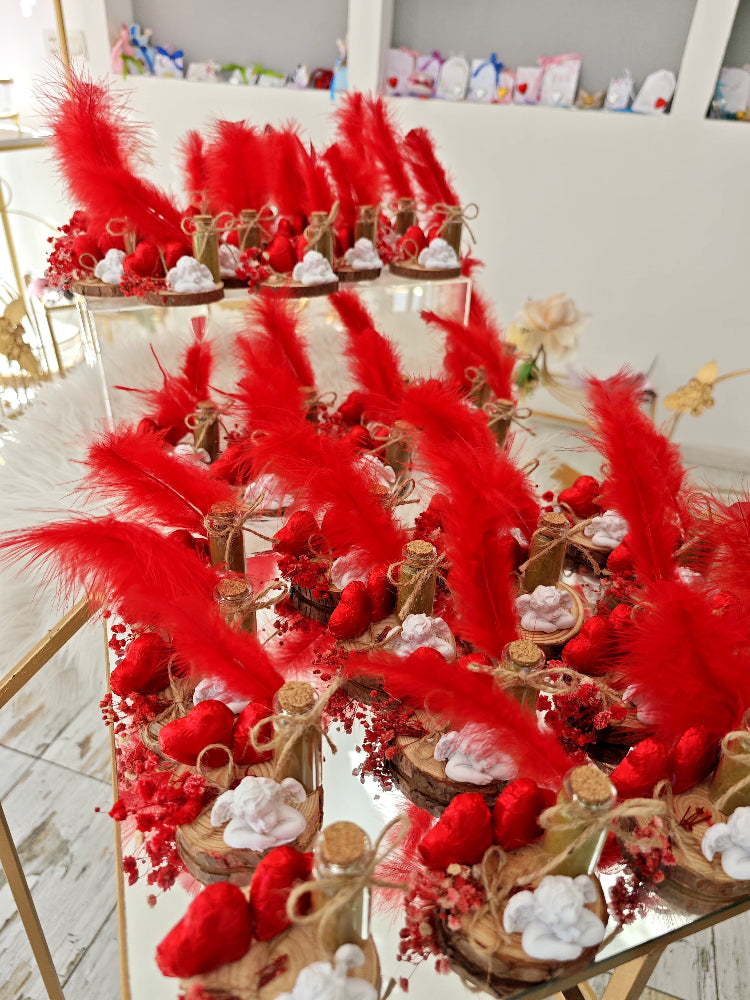 Decorative table setup with red feathers and heart-shaped items on a white surface.