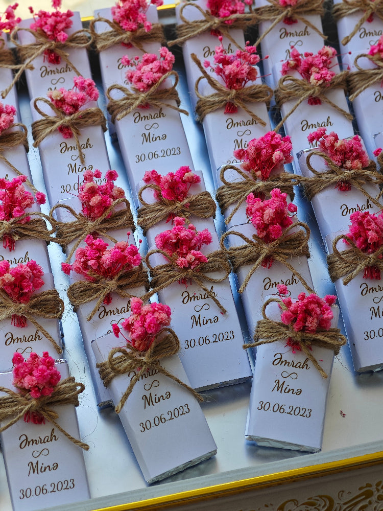 Small boxes with pink flowers and personalized text on a white surface