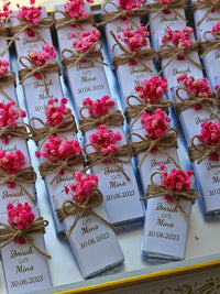 Small boxes with pink flowers and personalized text on a white surface