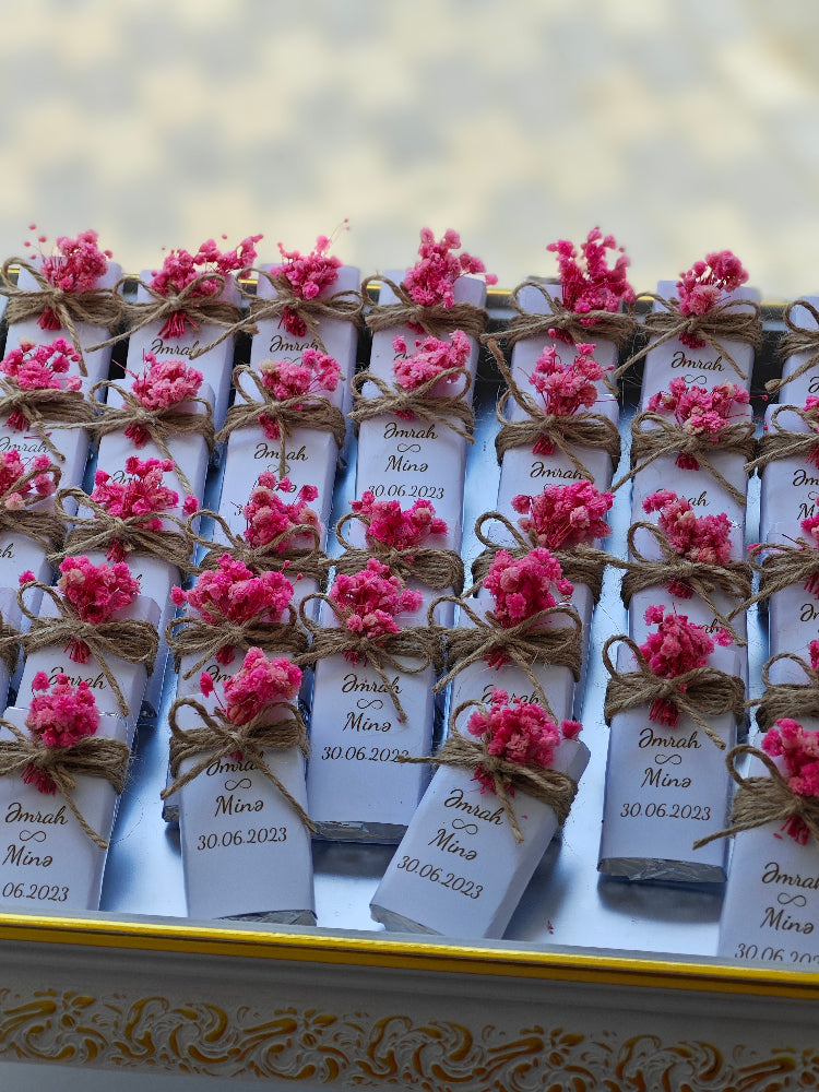 Small boxes with pink flowers and labels on a decorative surface