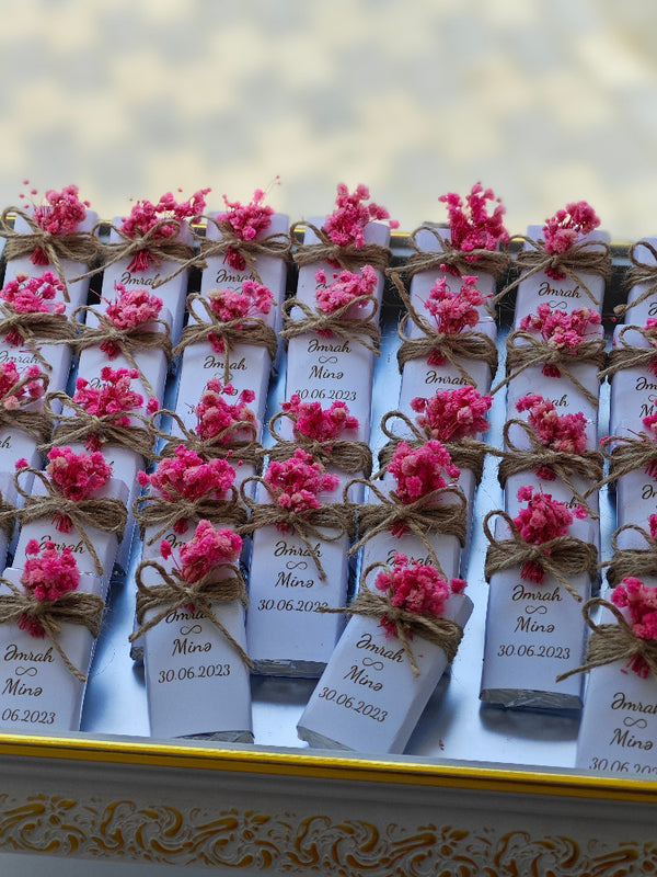 Small boxes with pink flowers and labels on a decorative surface