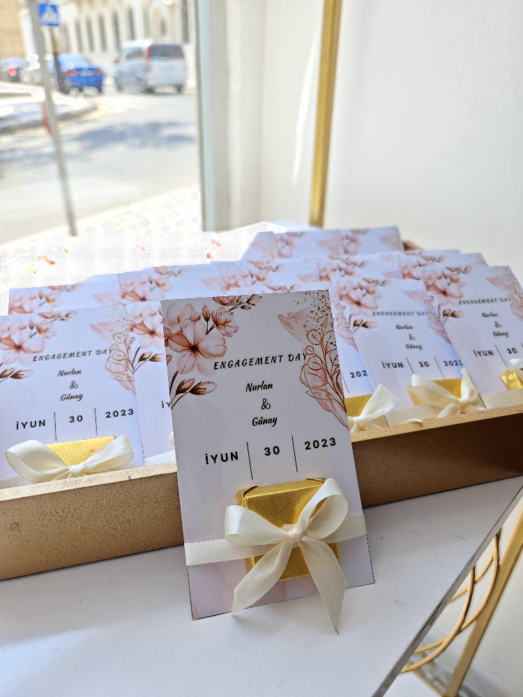 Engagement day invitation cards with floral designs and ribbons on a white surface.