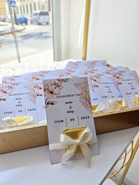 Engagement day invitation cards with floral designs and ribbons on a white surface.