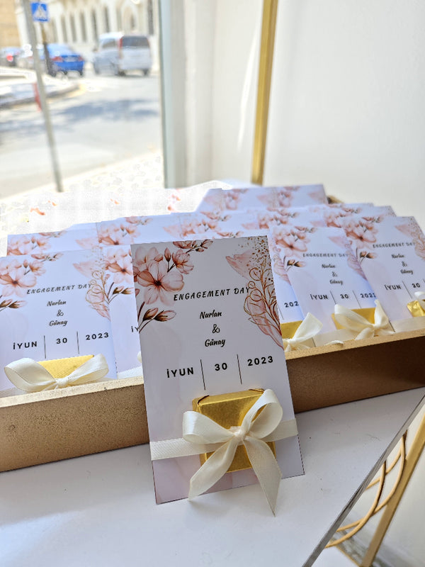 Engagement day invitation cards with floral designs and ribbons on a white surface.