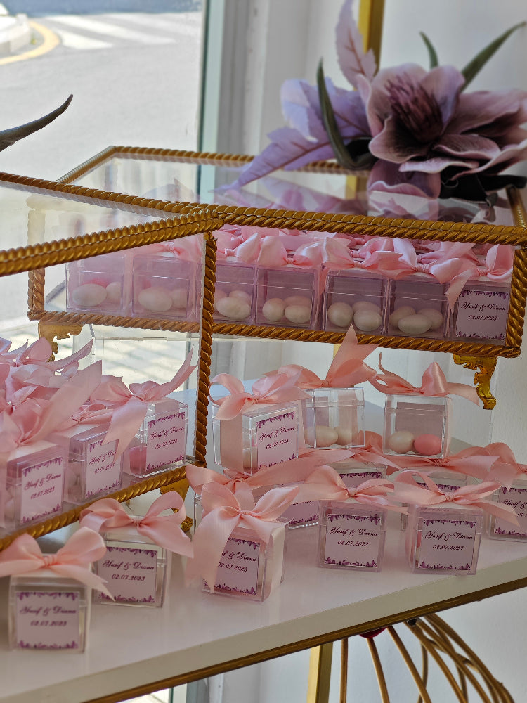 Decorative display of small boxes with pink ribbons on a glass shelf.