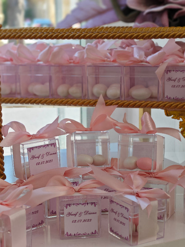 Clear containers with pink ribbons and labels on a gold stand.