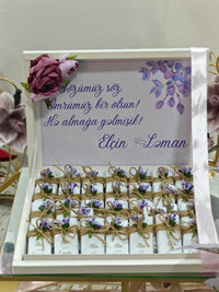 Gift set with white boxes, purple flowers, and a card on a white background