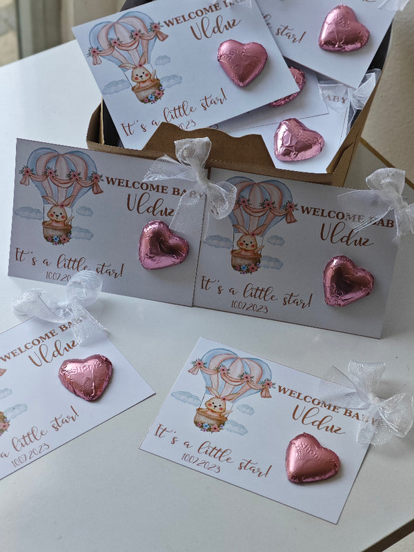 Pink heart-shaped earrings on baby shower cards with 'Welcome Baby' text.