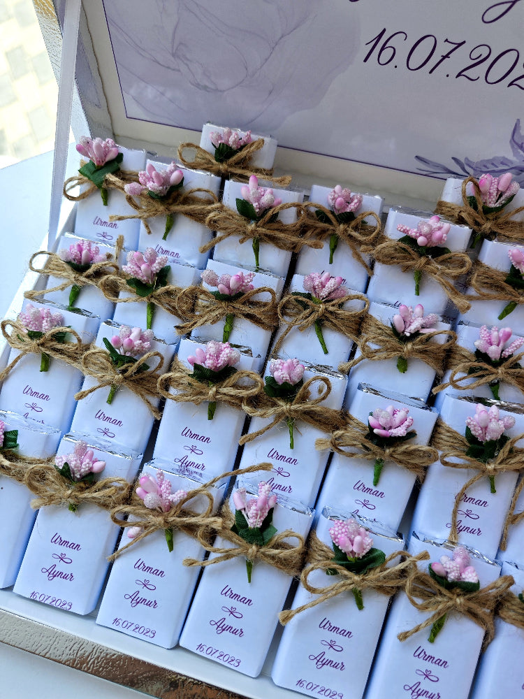 Set of small chocolates with floral decorations and labels, tied together with twine.