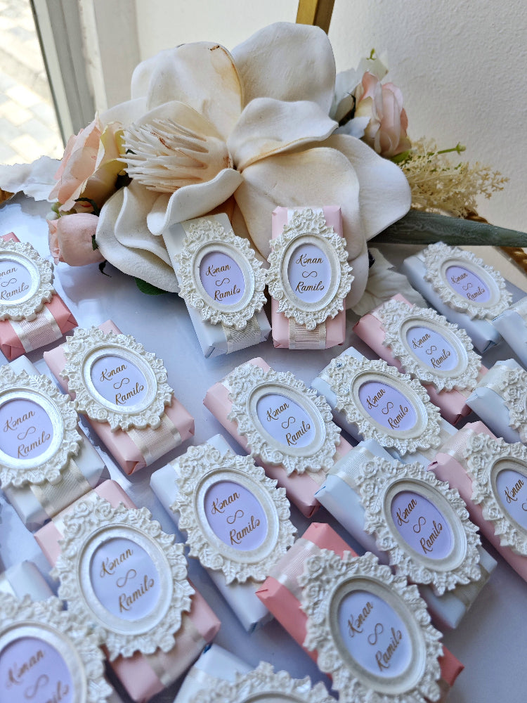 Decorative soap bars with decorative labels and a large flower arrangement in the background.