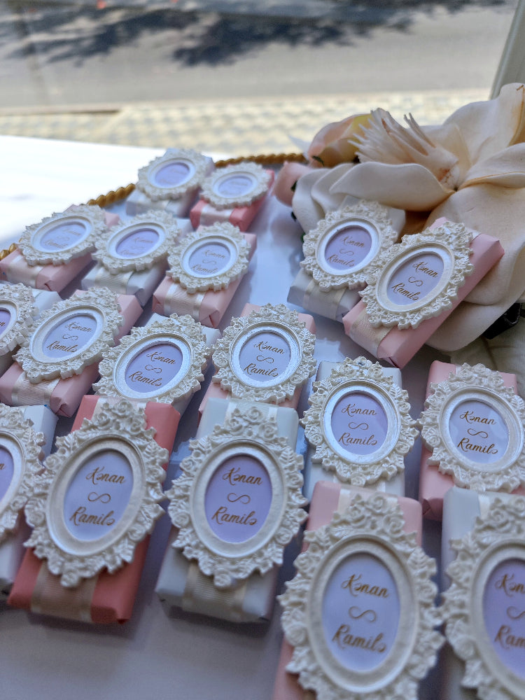 Decorative soap bars with ornate frames and personalized labels on a white surface.