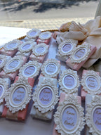 Decorative soap bars with ornate frames and personalized labels on a white surface.