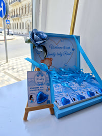 Baby shower gift set with blue ribbons and decorative elements on a table.