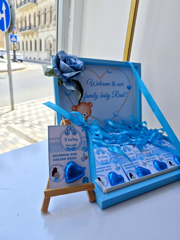 Baby shower gift set with blue ribbons and decorative elements on a table.