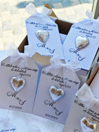 Heart-shaped earrings in packaging with personalized text on a blurred outdoor background