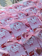 Gift boxes with pink ribbons and decorative labels on a checkered surface.