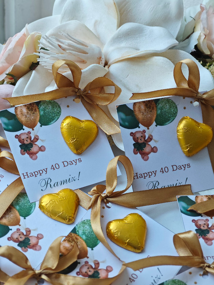 Gold heart-shaped chocolates with ribbons and personalized cards on a white background