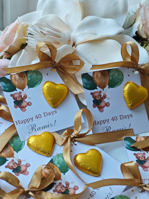 Gold heart-shaped chocolates with ribbons and personalized cards on a white background