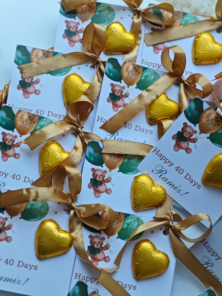 Gold heart-shaped chocolates with ribbons on personalized cards for a 40th birthday celebration.