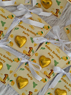 Gold heart-shaped chocolate candies with white ribbons on 'Afhila's Birthday Party' cards.