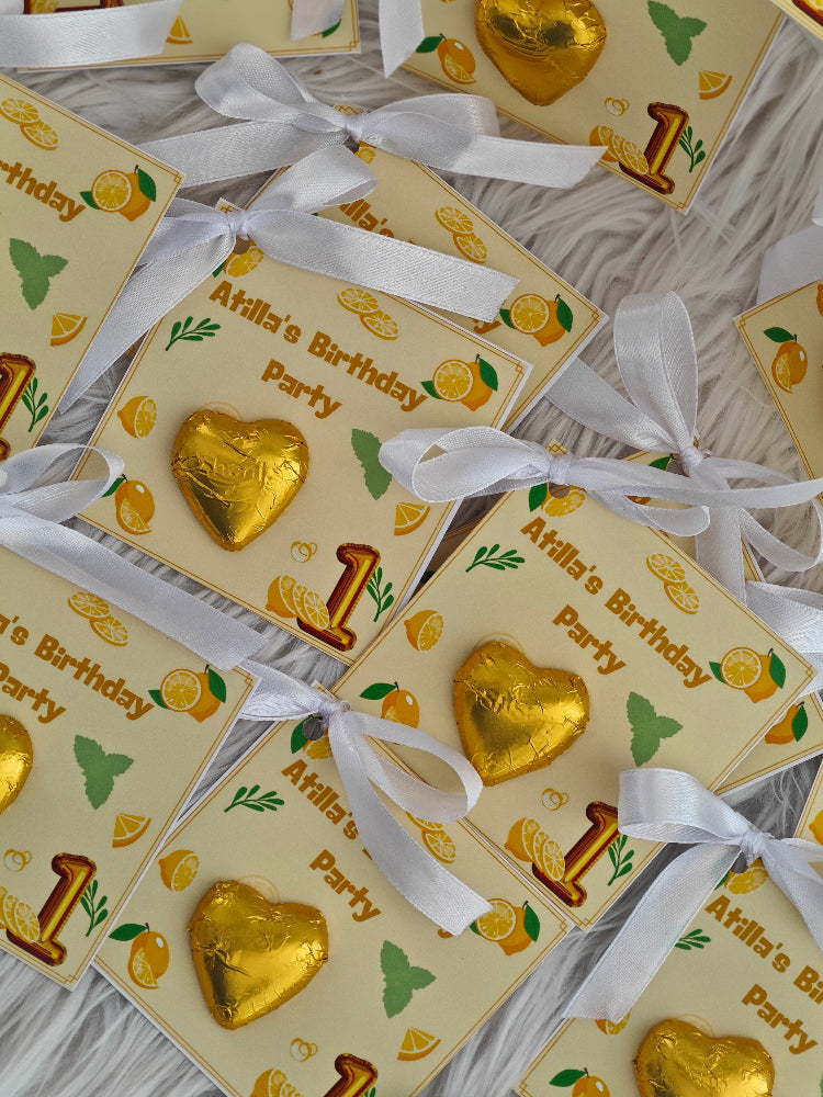 Gold heart-shaped chocolate candies with white ribbons on 'Afhila's Birthday Party' cards.