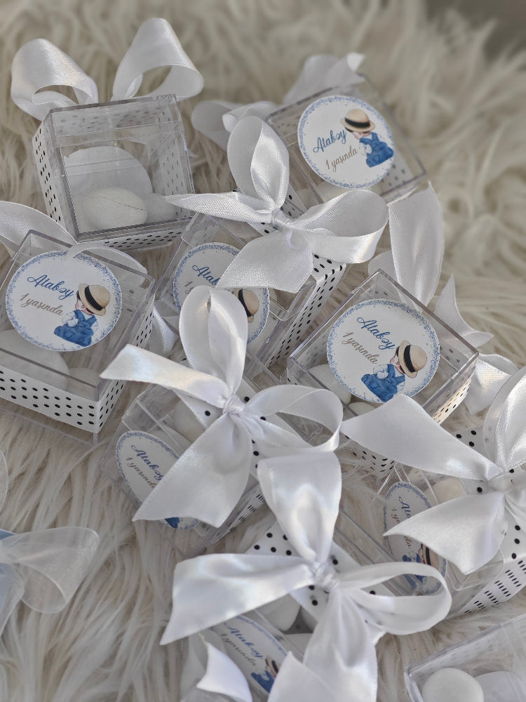 Small decorative boxes with white ribbons on a textured surface