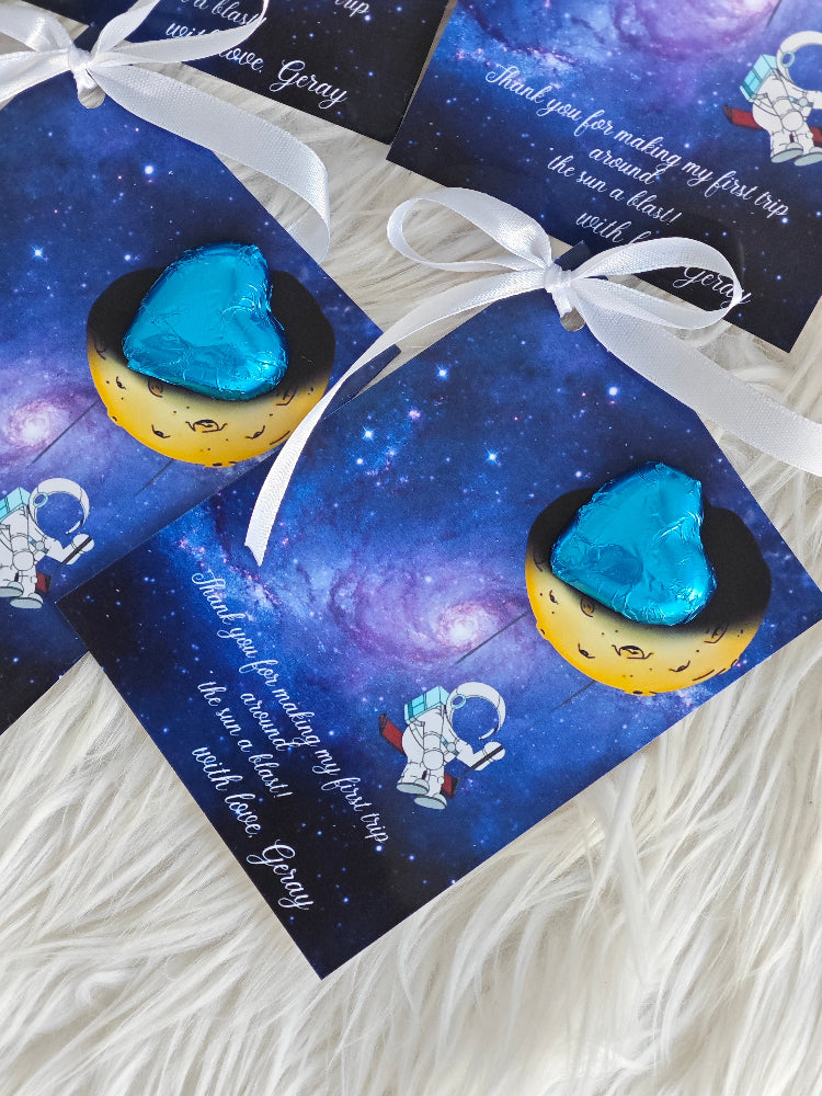 Space-themed cards with blue rocks on yellow moons, tied with white ribbons.