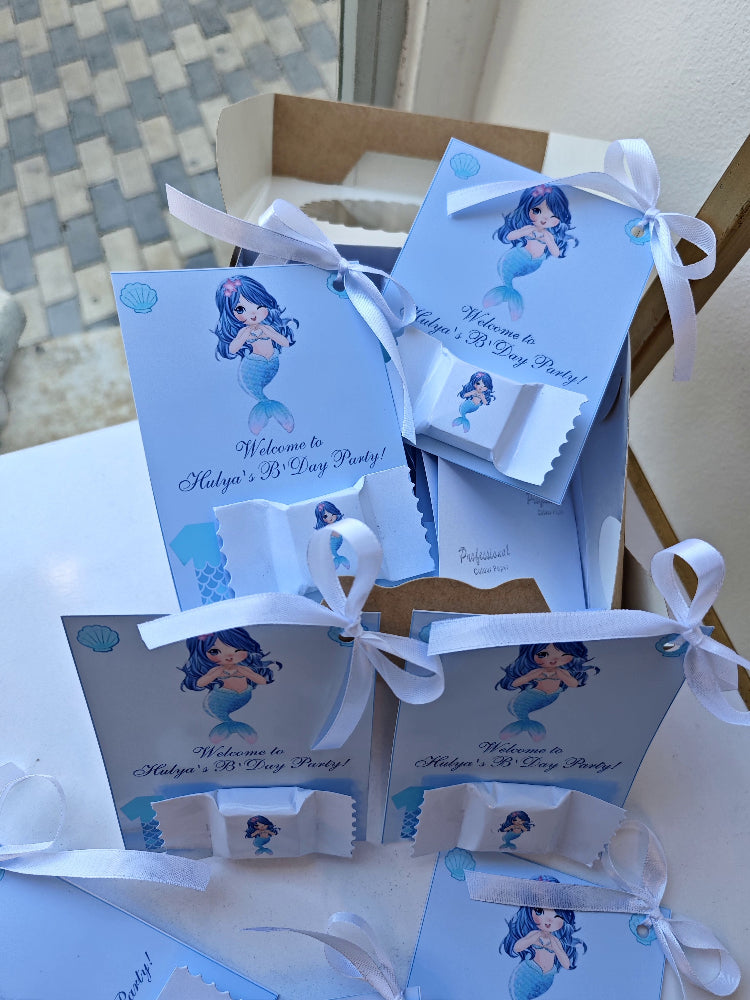 Set of mermaid-themed party invitations with ribbons on a textured surface.