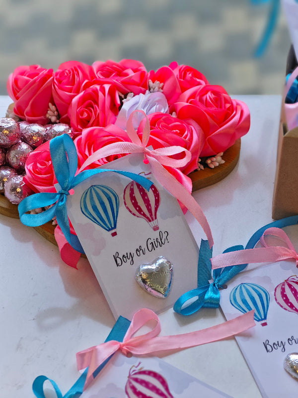 Heart-shaped arrangement of pink roses with ribbons and a 'Boy or Girl?' card.