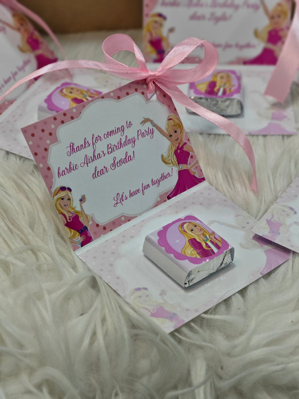 Barbie-themed birthday party favor with candy and card on a white surface