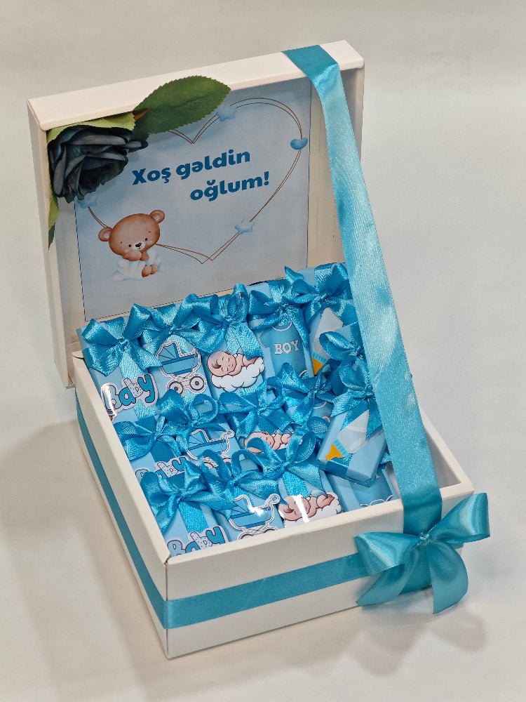 Gift box with blue ribbon and baby-themed items on a white background