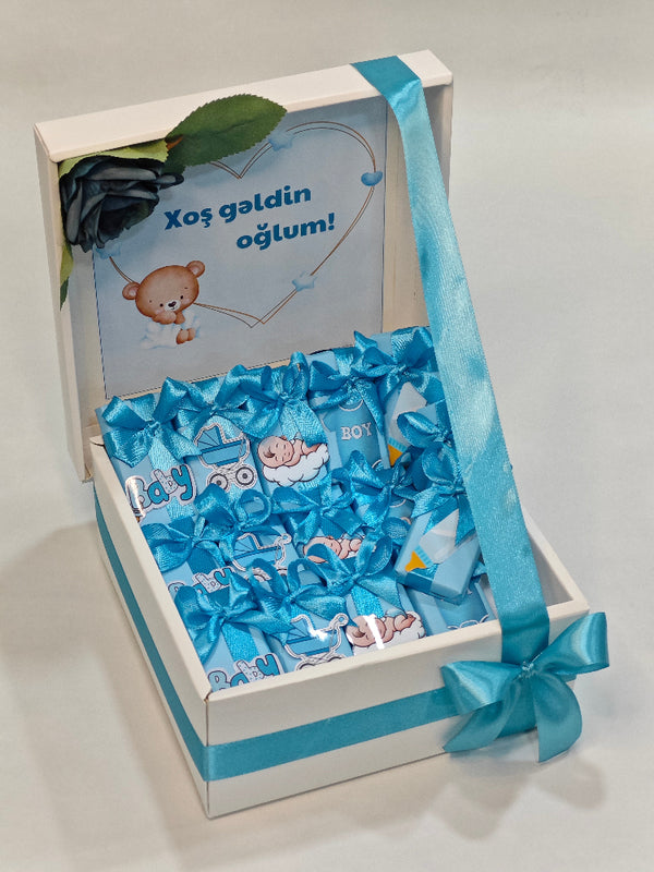 Gift box with blue ribbon and baby-themed items on a white background
