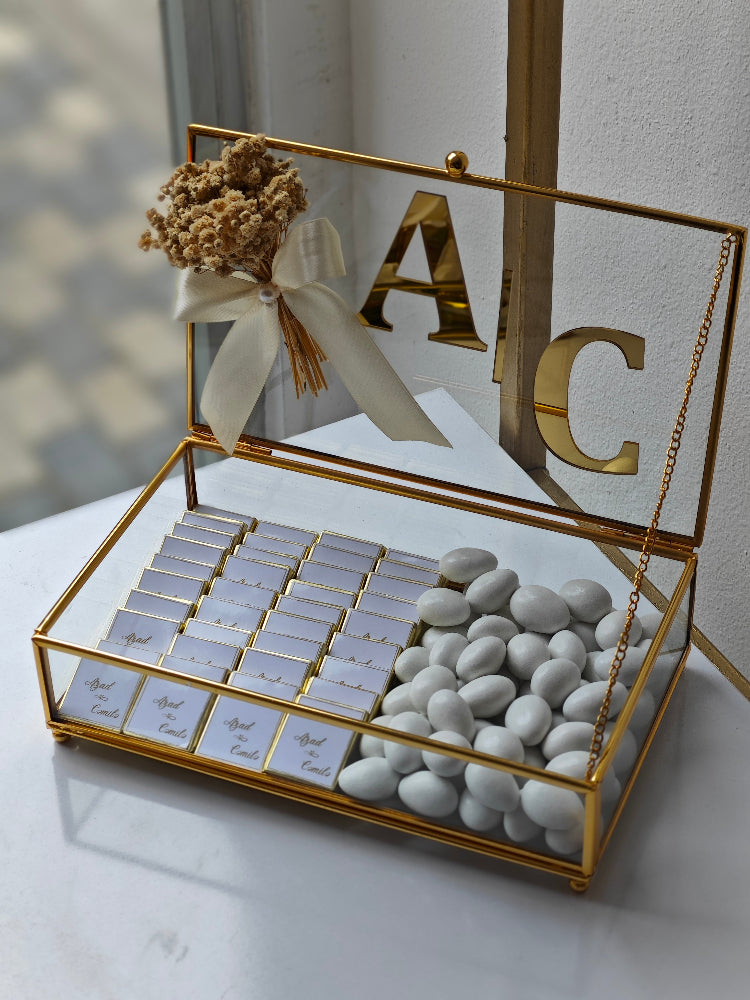 Decorative box with gold accents, white stones, and small cards on a light surface.