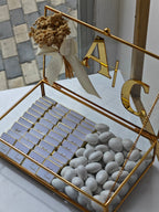 Decorative box with gold accents containing small items, placed on a surface with a blurred background.