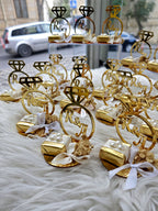 Gold wedding ring-shaped favors with 'R&A' initials on a white surface.