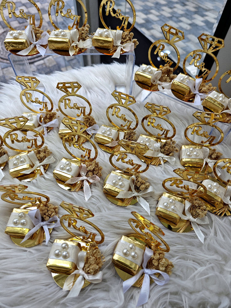 Gold jewelry display with 'Raj' branding on a white surface