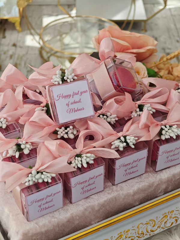 Small gift boxes with pink ribbons and flowers on a decorative surface.