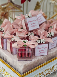 Decorative boxes with pink ribbons and macarons on a decorative stand.