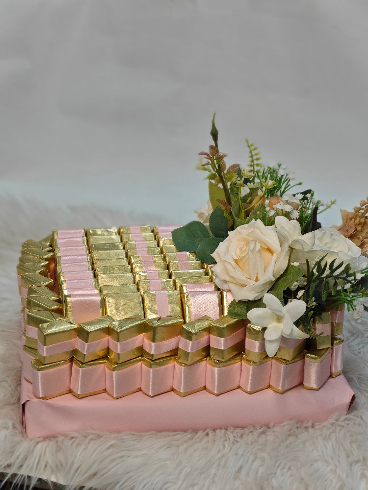 Decorative arrangement of gold and pink boxes with flowers on a white surface