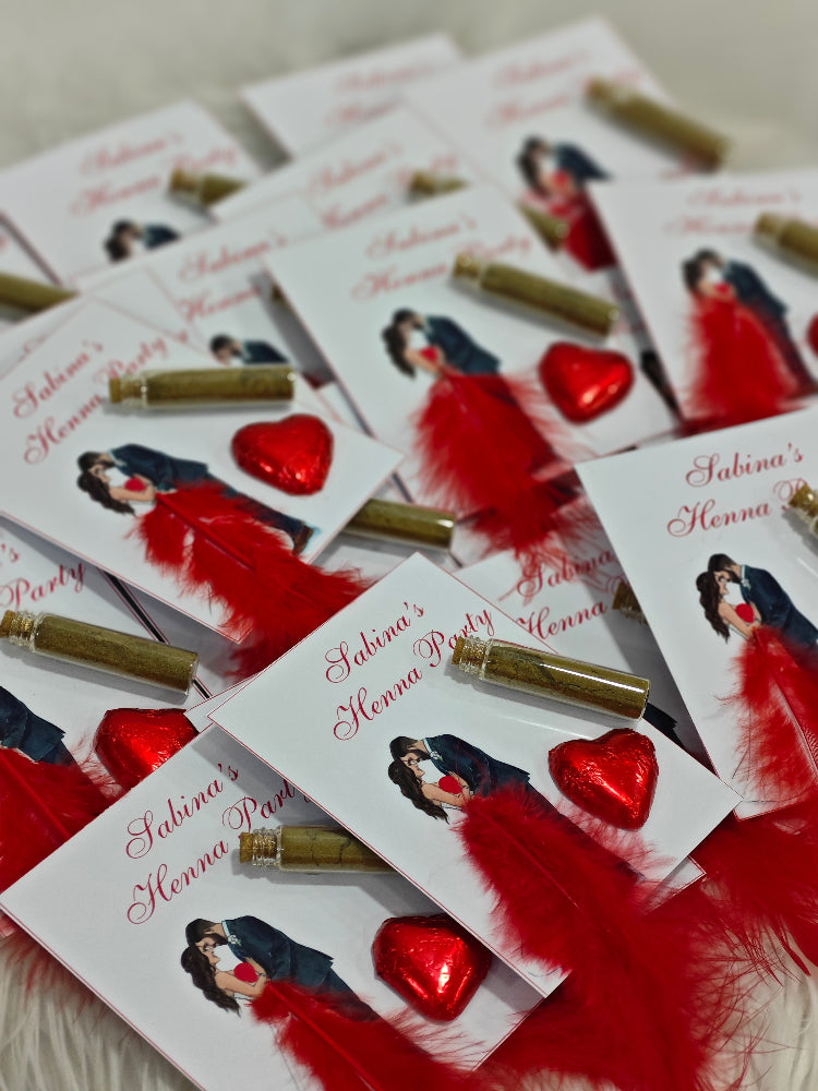 Henna party invitations with red feathers and heart decorations on a white surface