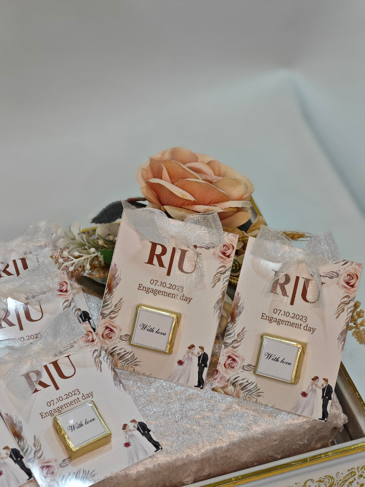 Decorative bags with 'RJU' branding and floral designs on a white surface.
