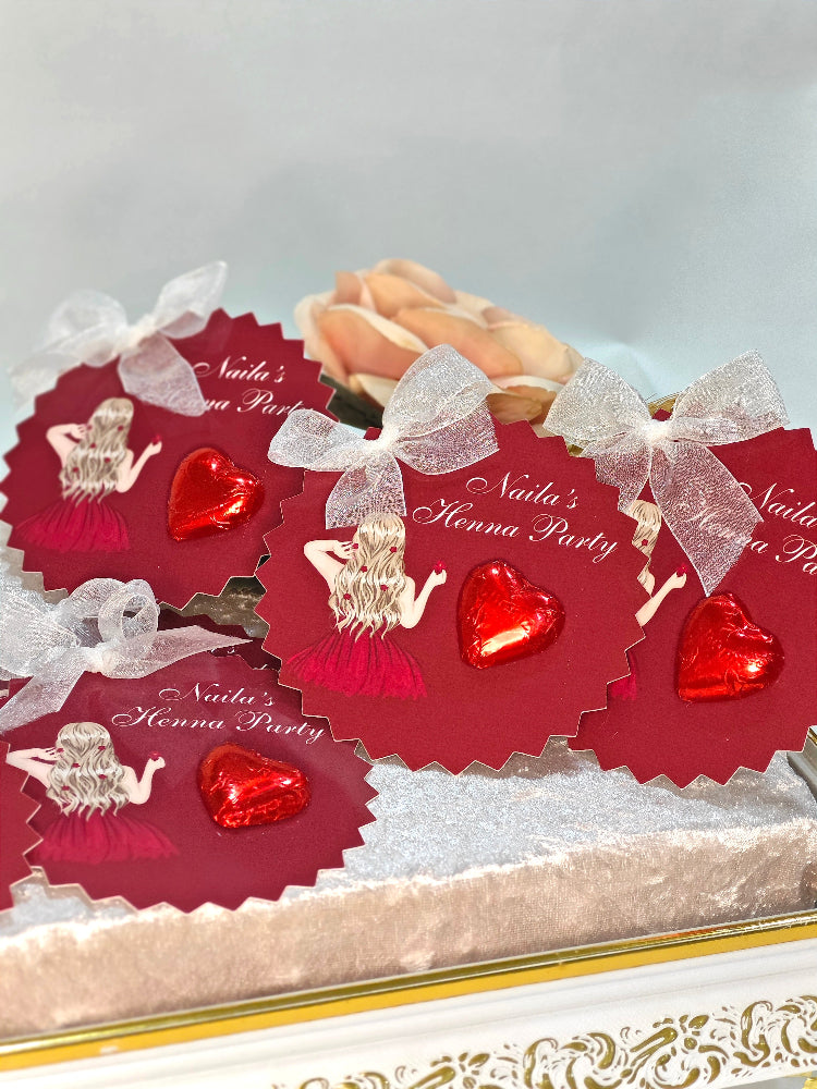 Decorative box with red hearts and gold figures, labeled 'Nadia's Henna Party', on a white background.